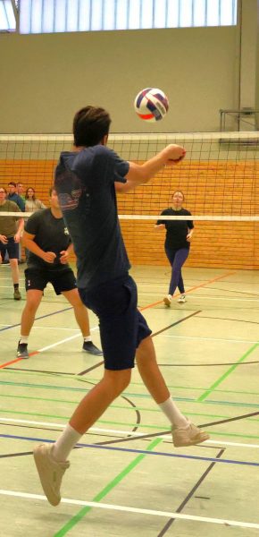 Spieler nimmt den Volleyball an und spielt ihn zu einem Mitspieler der am Netz wartet.