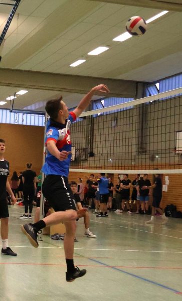 Ein Volleyballspieler springt am Netz hoch spielt den Ball über das Netz.