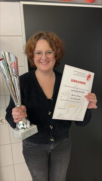 Yvonne Körner mit dem Pokal in der rechten Hand und der Urkunde in der linken Hand für für ihre Goldmedaille beim Leistungswettbewerb der Flesicherjugend.