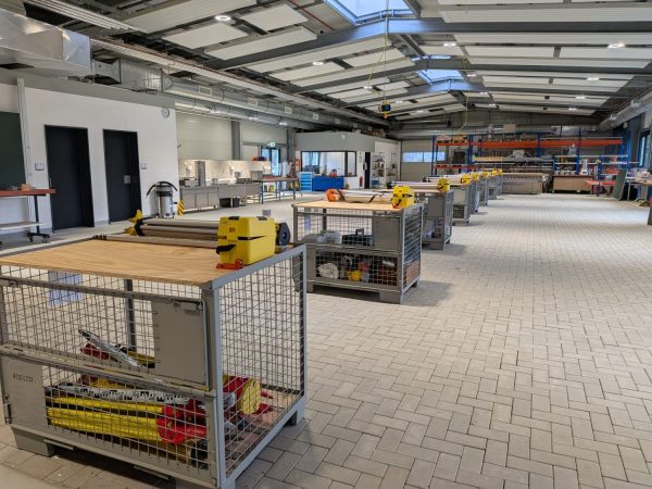 Mehrere Werkbänke mit modernen Nivellierungsinstrumenten und Bauwerkzeugen stehen in einer geräumigen Bauwerkstatt des BBZ am NOK.